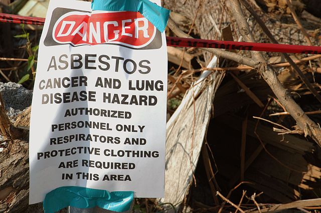 Asbestos caution sign next to pile of debris