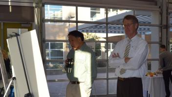 Two men stand in front of large posters reading them intently