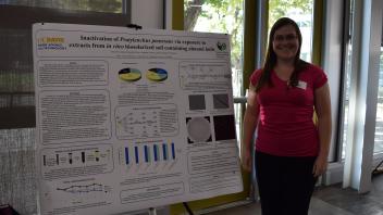 smiling woman stands next to poster