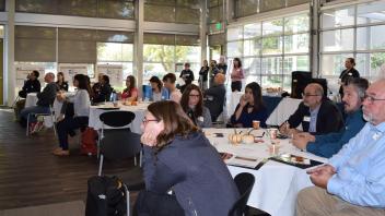 broad shot of audience sitting in chairs at round tables listening to talks