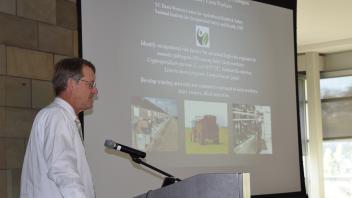 Dr. Rob Atwill stands at podium in front of screen showing opening slide in presentation
