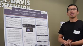 Man stands with hands clasped next to research poster