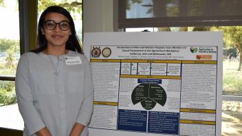 Woman stands with hands clasped next to research poster