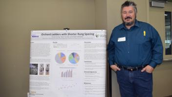Man stands with hands in his pockets next to his research poster