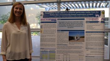 smiling woman stands next to her research poster