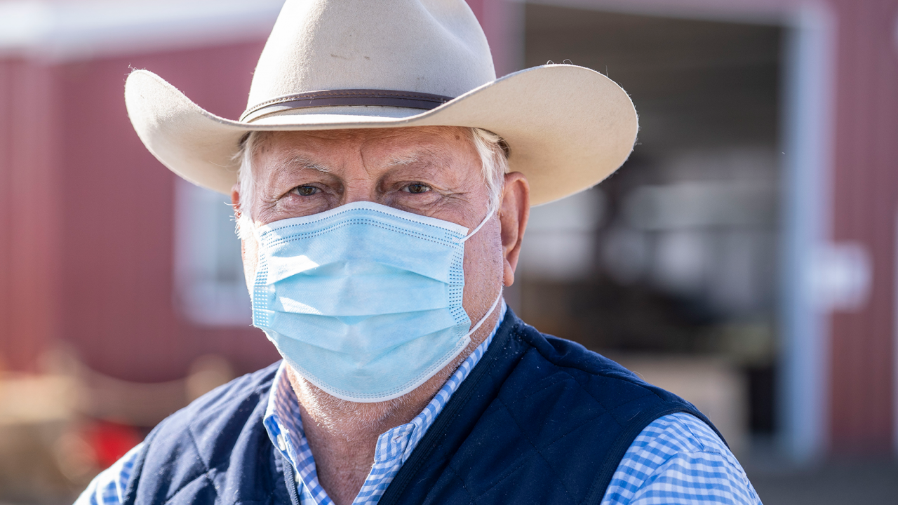 A farmer wears a cowboy hat and a surgical mask