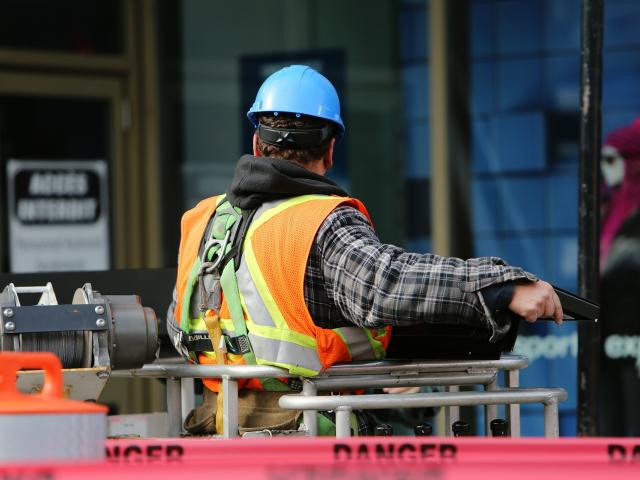 Construction worker in a safety vest faces away from camera