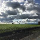 A field in Davis, CA with clouds in the sky