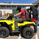 Photograph of yellow ATV with person sitting astride ATV and researcher adding a CPD