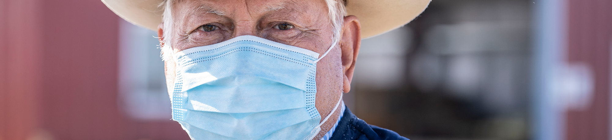 A farmer wears a cowboy hat and a surgical mask