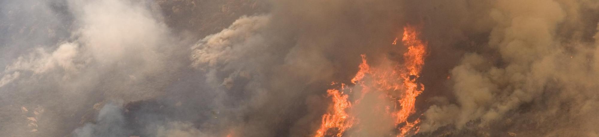 A helicopter drops water on the wildfire in California